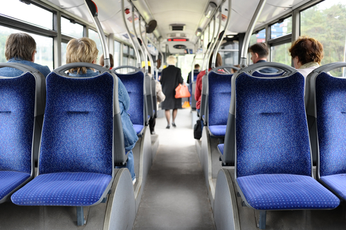 Interior of a public bus with blue seats and several passengers seated.